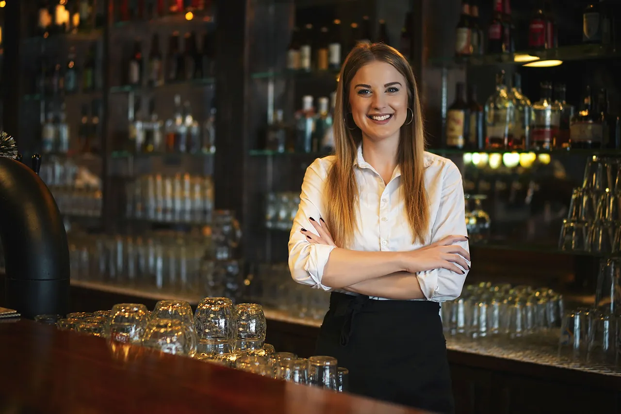 Female bartender standing behind bar